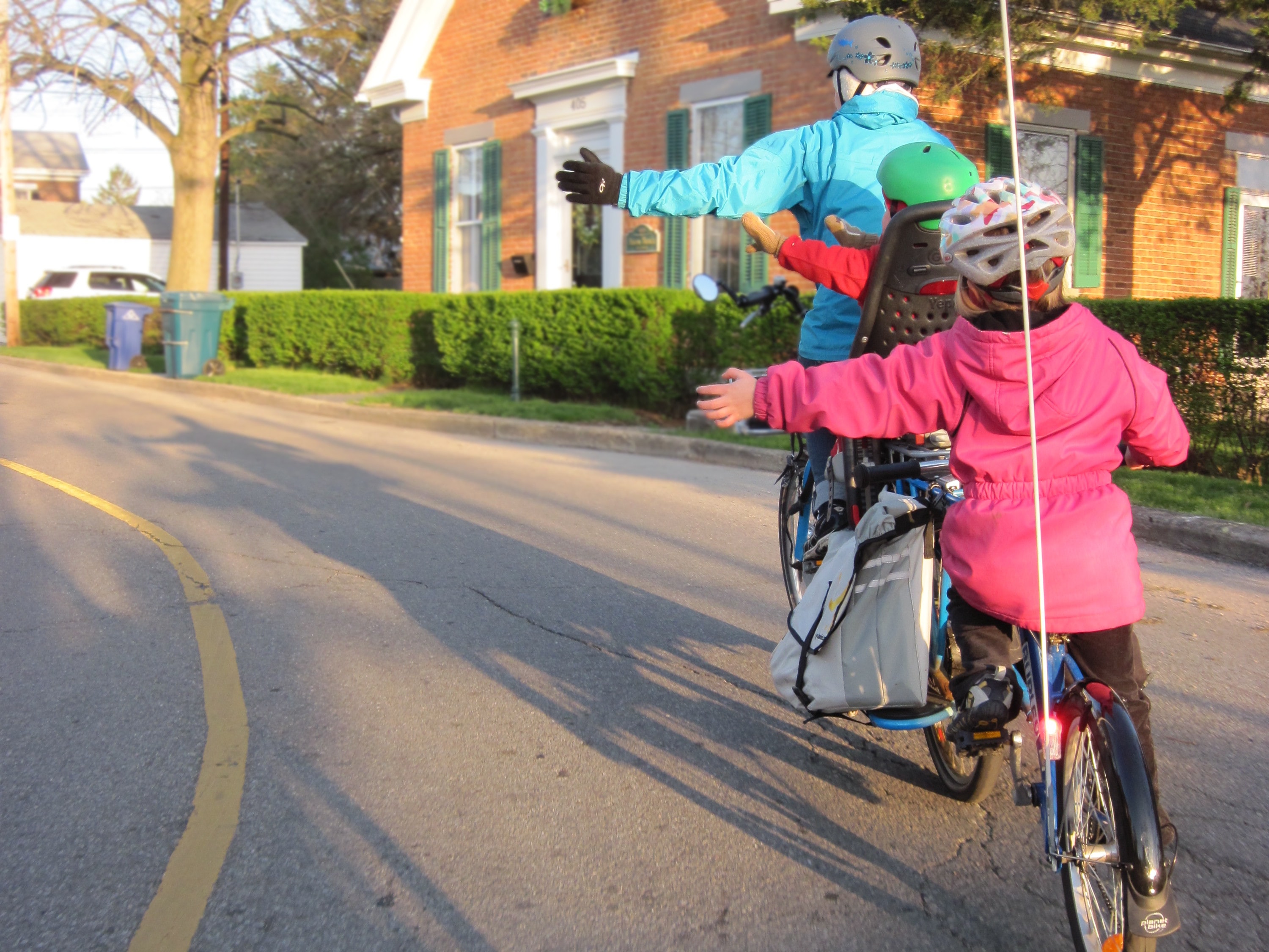 Parent and children riding bicycles near house