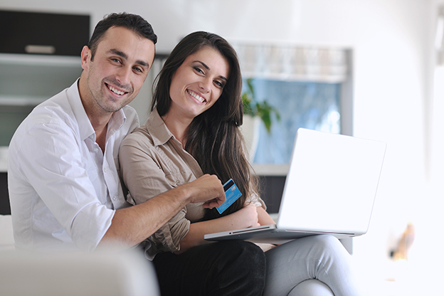 couple relaxing on couch building their credit on laptop