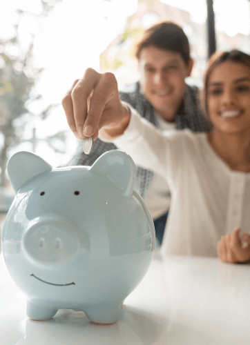 Happy woman putting coin in blue piggy bank