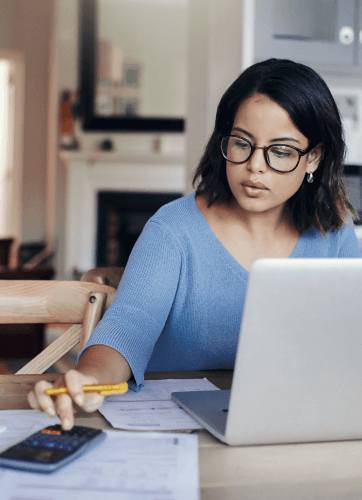 Woman with glasses using cell phone and laptop