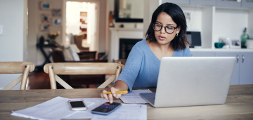 Woman wearing glasses on her laptop and using a calculator