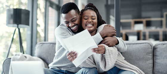 Happy husband hugging happy wife while wife hold paper