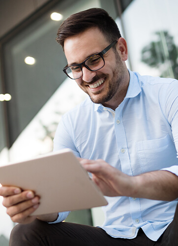 Man in glasses smiling while using computer tablet