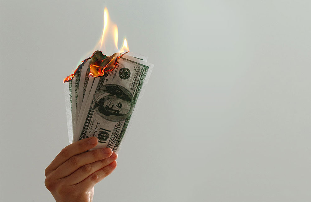 Hand holding money on fire