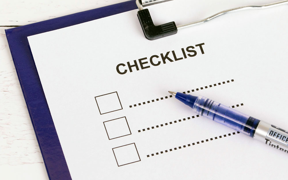 A blue pen on a paper with Checklist written on it
