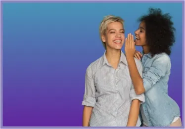 Two Women smiling. One of the women whispering into ear of the other.